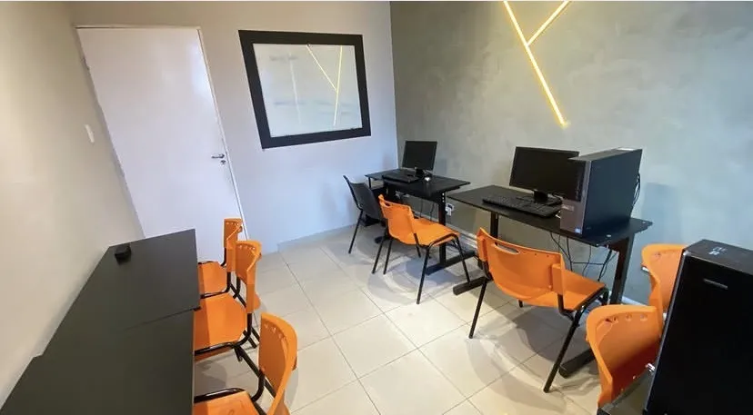 Sala de aula da unidade com cadeiras laranja e janelas amplas